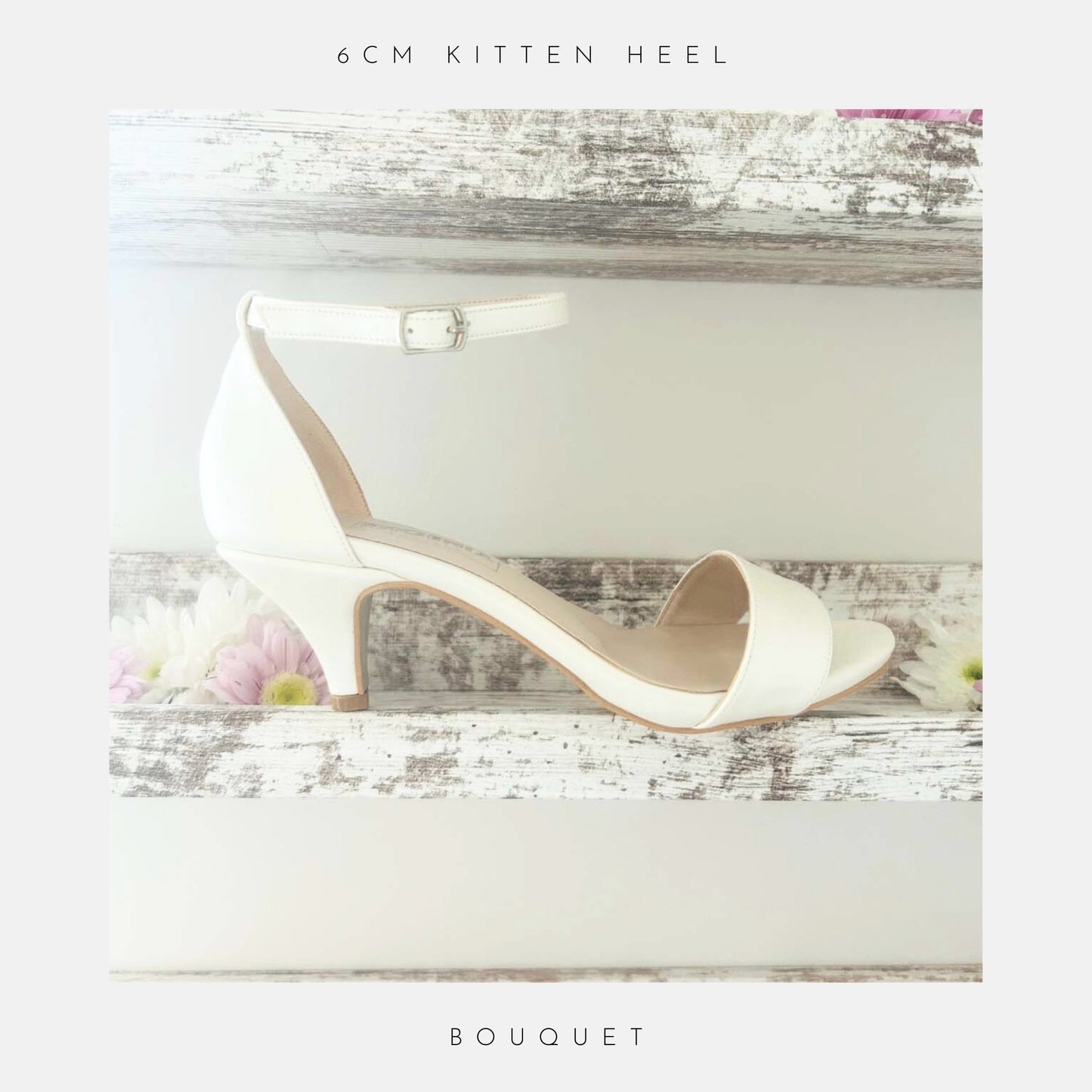 A pair of Bouquet Kitten Heel Bridal Shoes by Phoenix England in pearl vegan leather with an ankle strap rests on a rustic white shelf, surrounded by pink and white daisies.