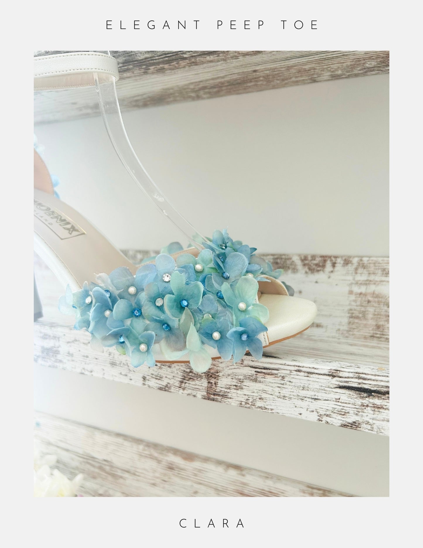 Ivory wedding sandal with blue floral decorations on a wooden surface, labelled 'Elegant Peep Toe Clara'.