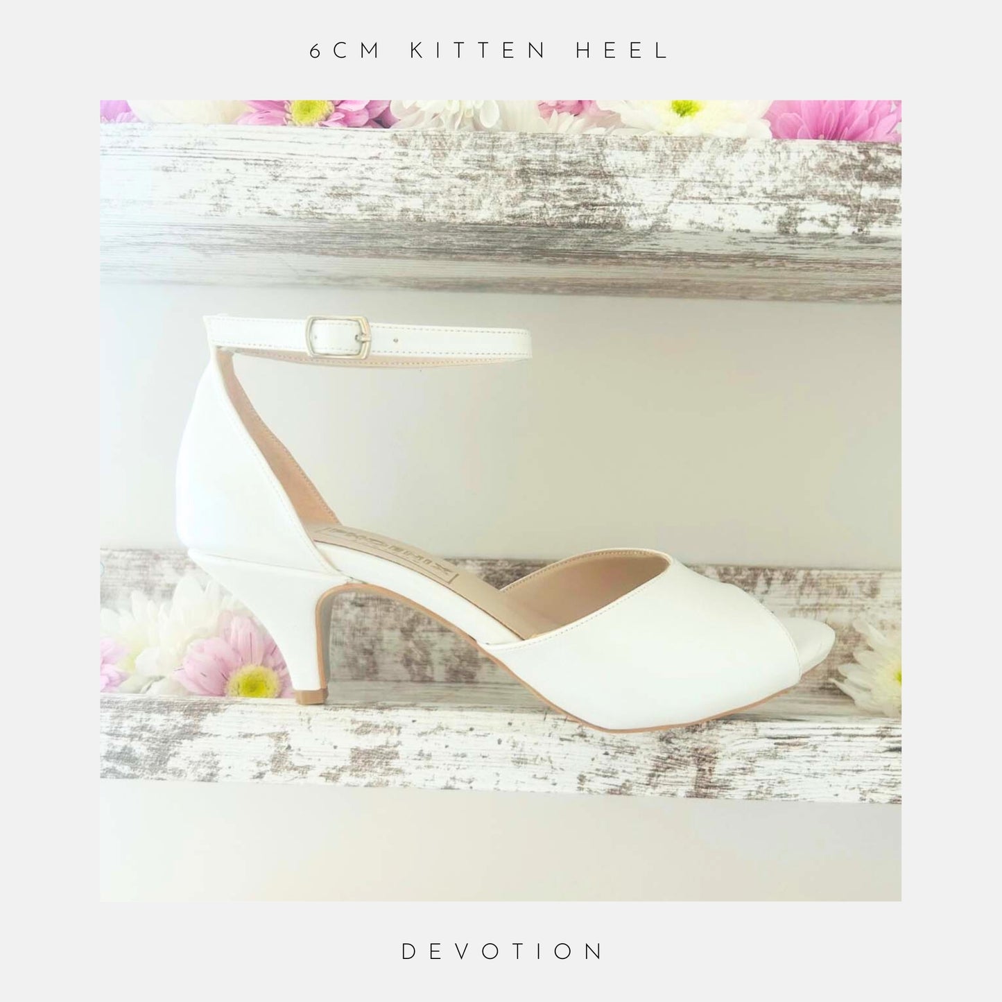 The Devotion Peep Toe Kitten Heel Bridal Shoes by Phoenix England sit on a rustic white shelf, surrounded by pastel pink and white flowers. Text reads, “6cm kitten heel – Devotion.”.