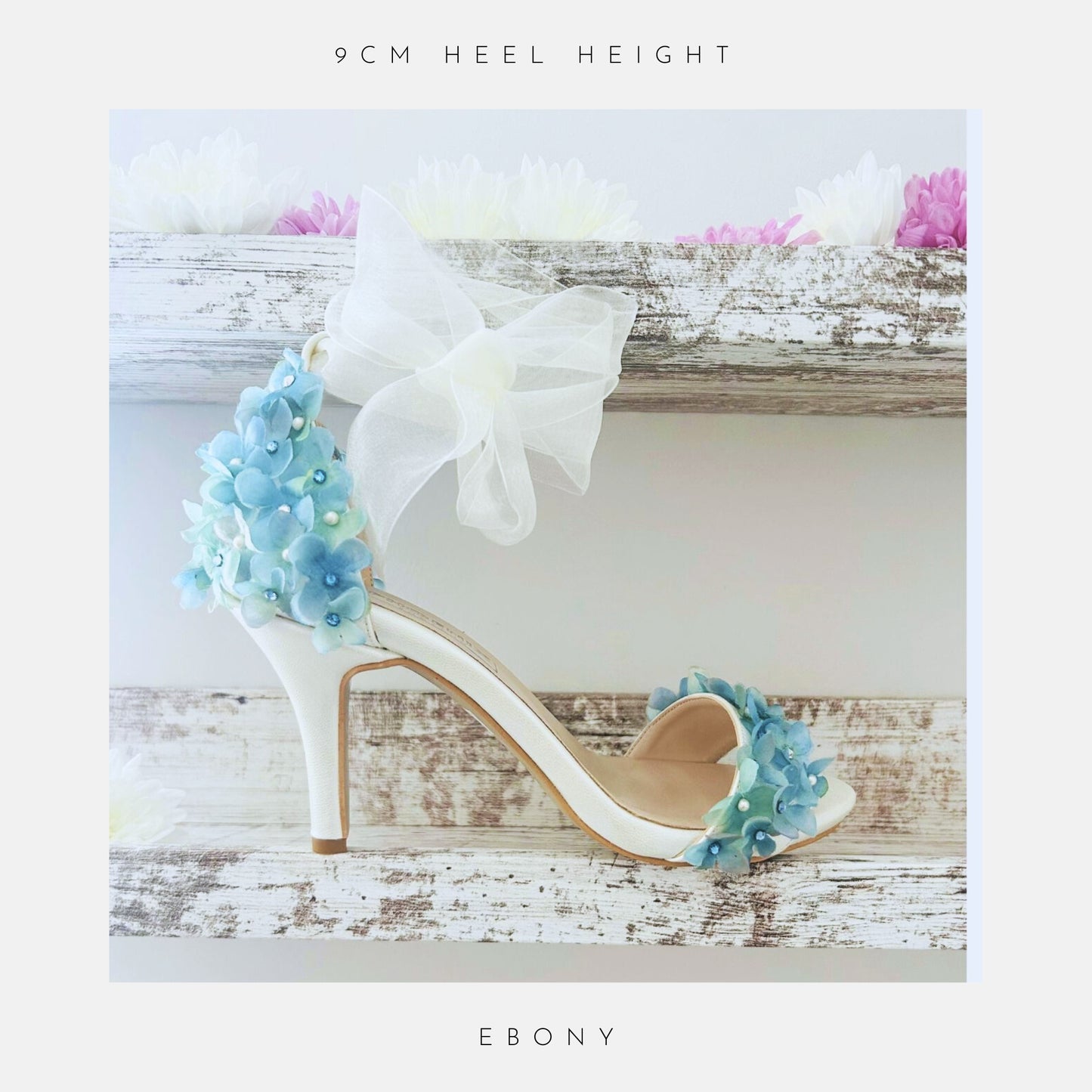 Ivory high-heeled bridal shoes with floral decorations on a wooden surface, labelled '9cm heel height' and 'Ebony'.