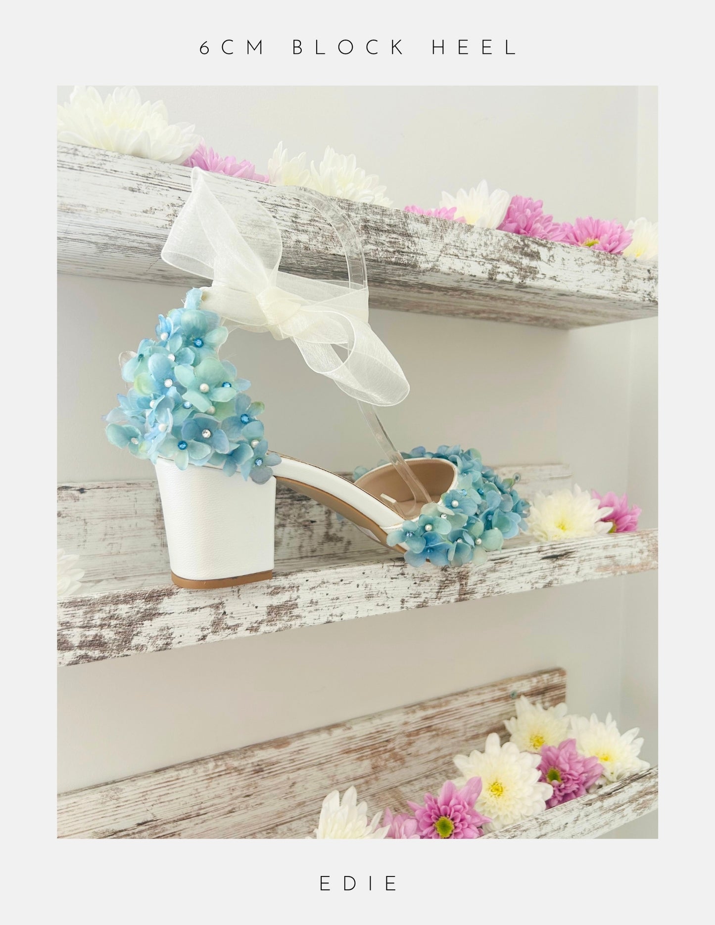 Ivory sandal with blue floral decorations on a wooden shelf with flowers.