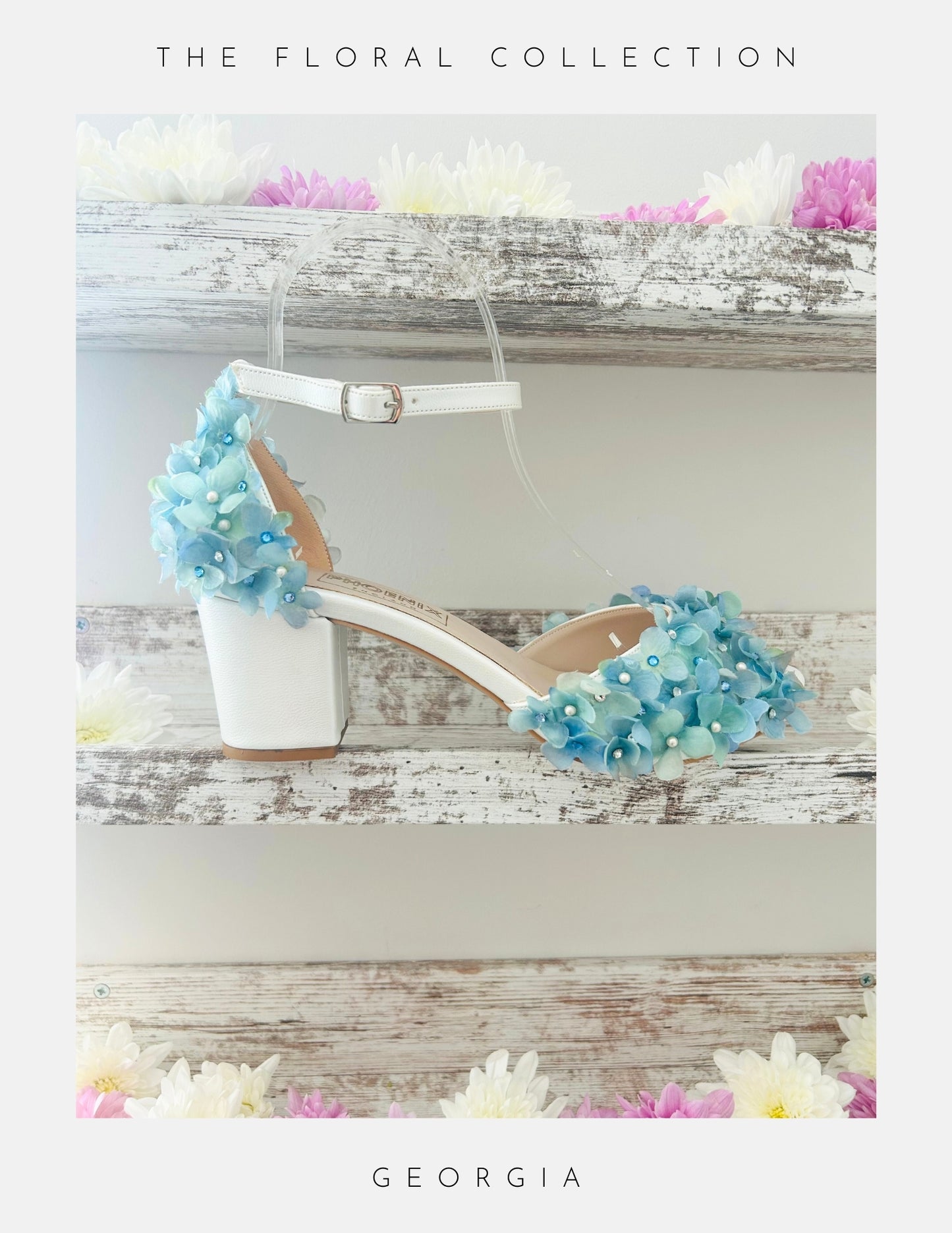 Ivory peep toe block heel bridal sandal with blue floral embellishments on a wooden surface with flowers.