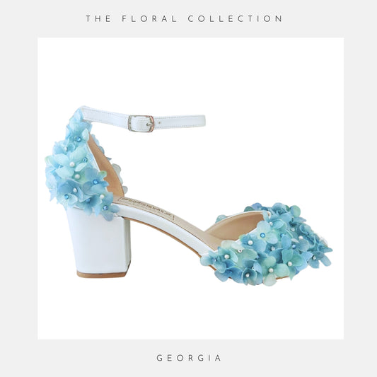 Ivory high-heeled shoe with blue floral embellishments on a white background