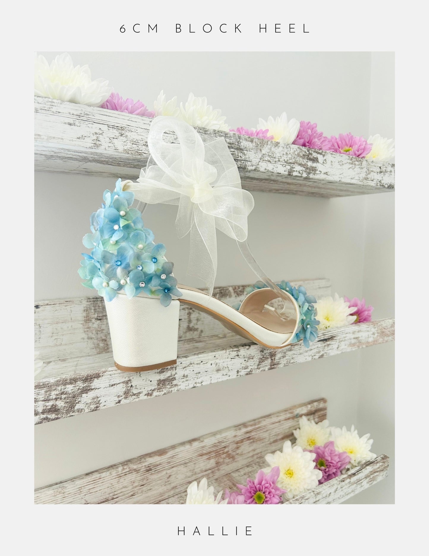 Ivory wedding sandal with floral decorations on a wooden shelf with flowers.