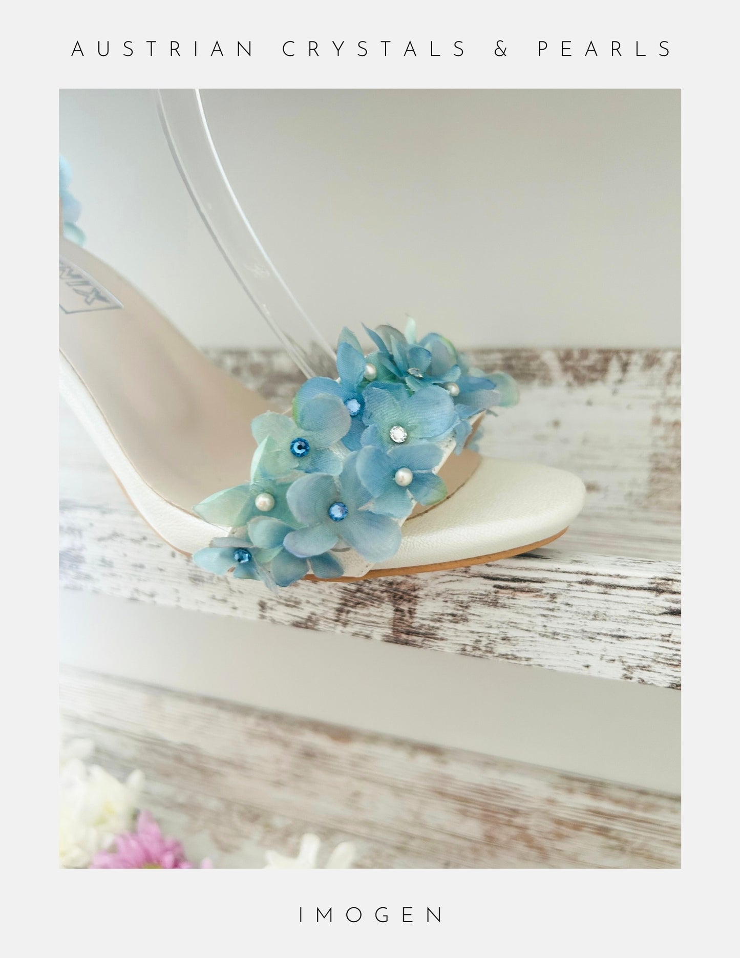 Ivory sandal with blue floral embellishments on a wooden surface, featuring 'Austrian Crystals & Pearls' text.