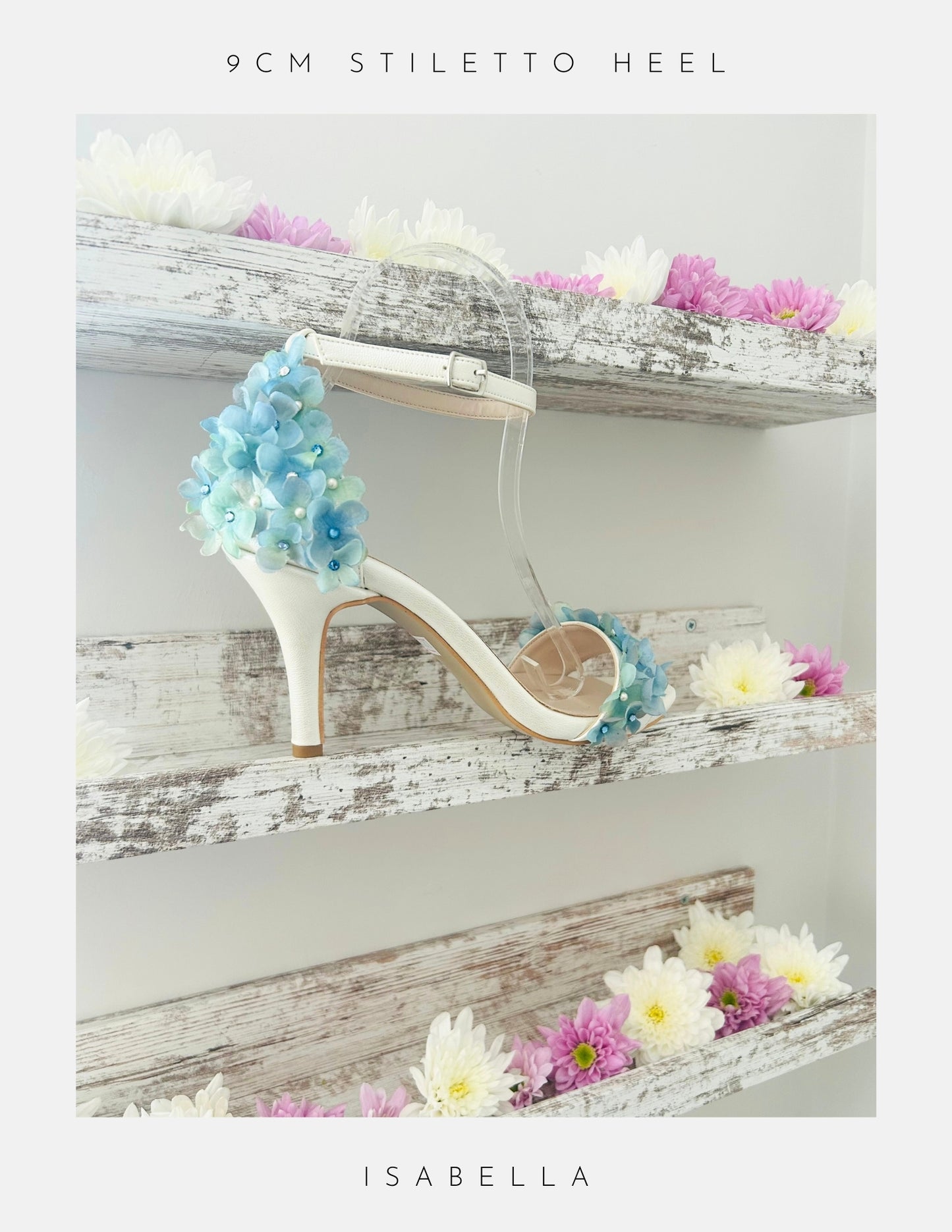 Ivory high-heeled bridal shoe with floral decorations on a wooden shelf with flowers.