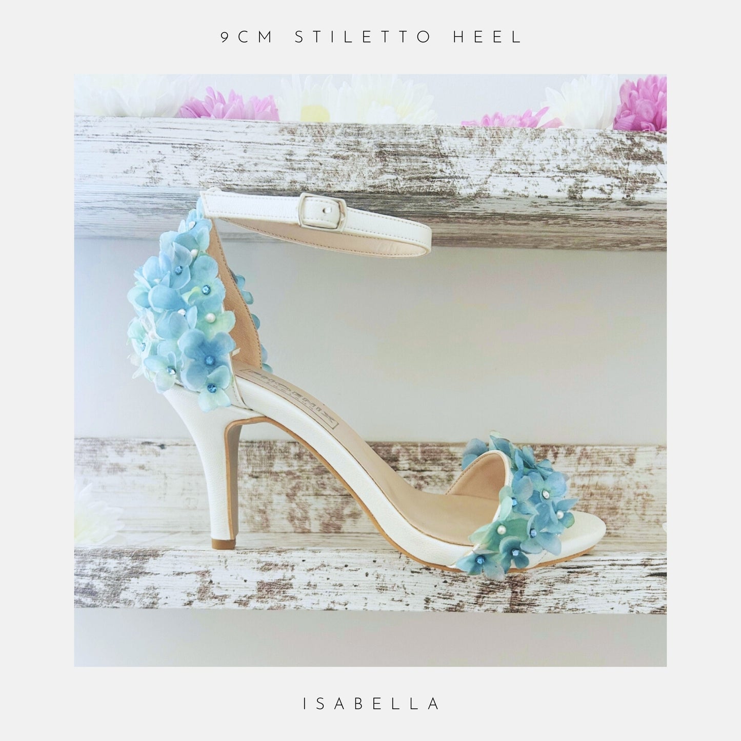Ivory bridal sandal with floral decorations on a wooden surface, labelled 'The Floral Collection' and 'Isabella'.