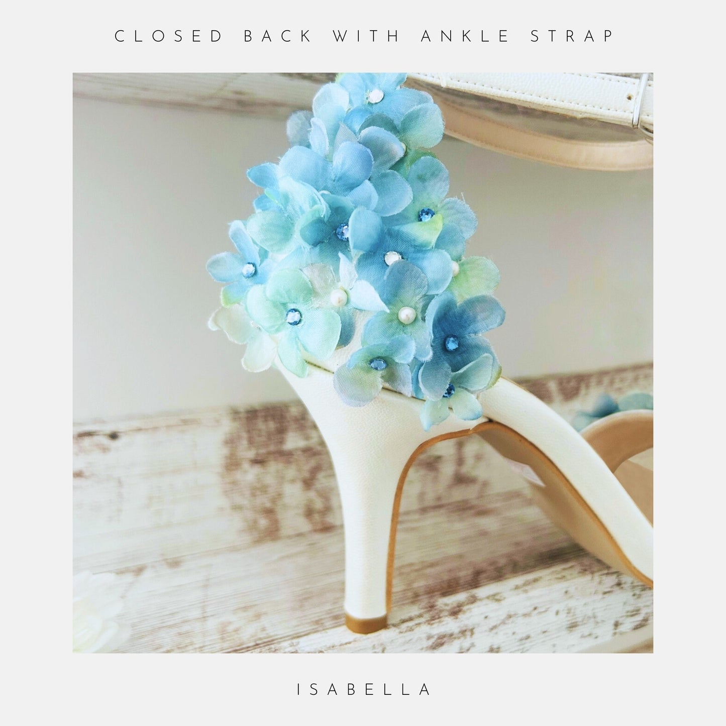 Ivory floral high-heeled wedding shoe with blue hand-applied hydrangeas on a wooden surface.