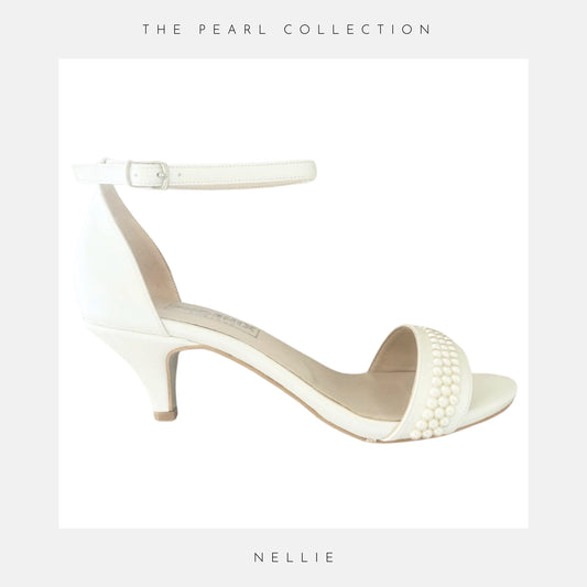 Ivory high-heeled sandal with pearl details on a light grey background, labelled 'NELLIE' from 'THE PEARL COLLECTION'.
