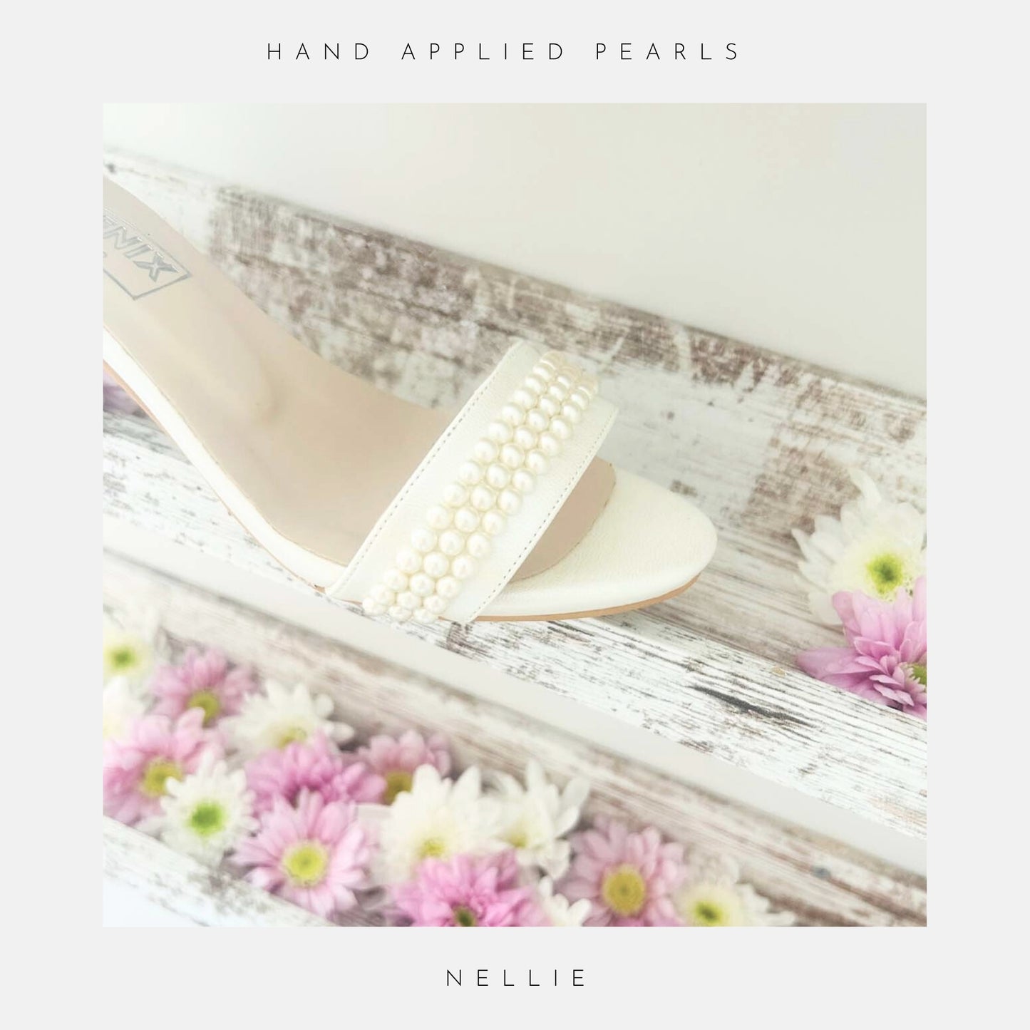 A close-up of Phoenix England’s Nellie Pearl Kitten Heel Bridal Shoes, featuring pearl-embellished ivory straps, shown on whitewashed wooden shelves with pink and white daisies. Text reads hand applied pearls, NELLIE at bottom.