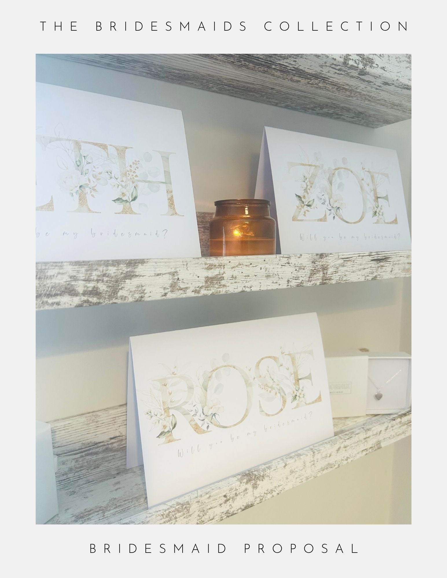 Three elegant Phoenix England cards with floral designs—Zoe, Rose, and LTH—are displayed on rustic shelves beside a brown candle. Each “Be My Bridesmaid card” features “Will you be my bridesmaid?” at the bottom.