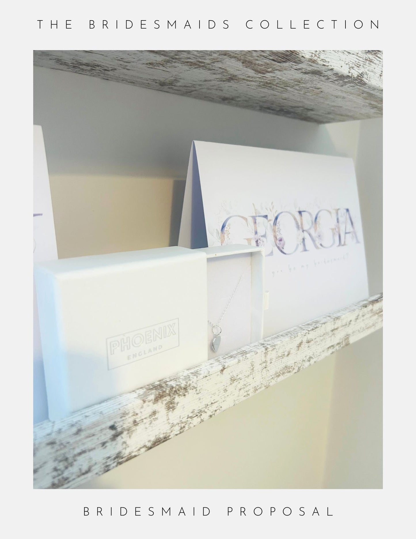 A Bridesmaids Proposal Sterling Silver necklace by Phoenix England rests in a white Phoenix England box on a rustic shelf beside a card labeled GEORGIA, featured as part of The Bridesmaids Collection.