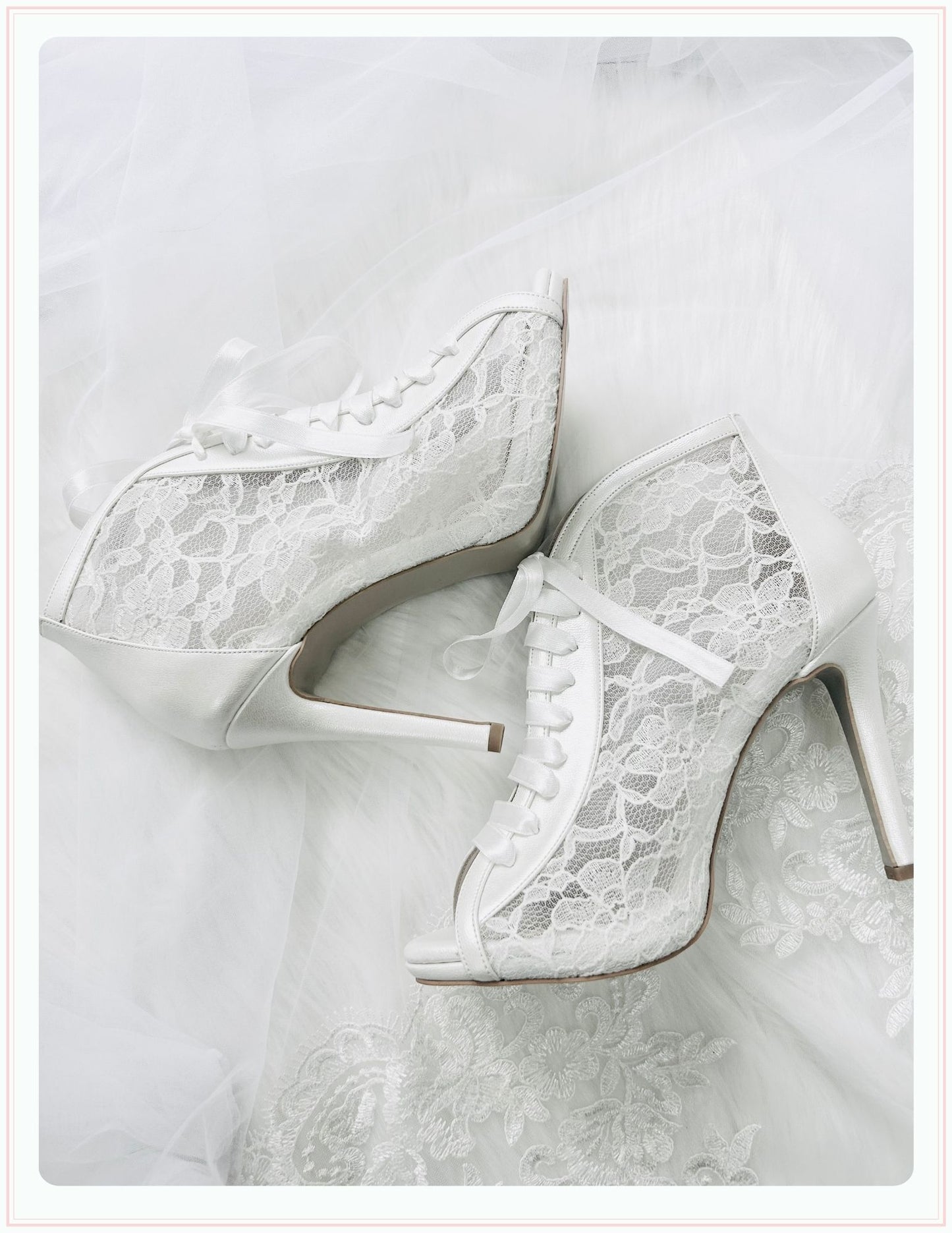The Phoenix England Chantilly Wedding Shoes feature white Chantilly lace, ribbon laces, and peep toes, beautifully displayed on sheer, delicate fabric.