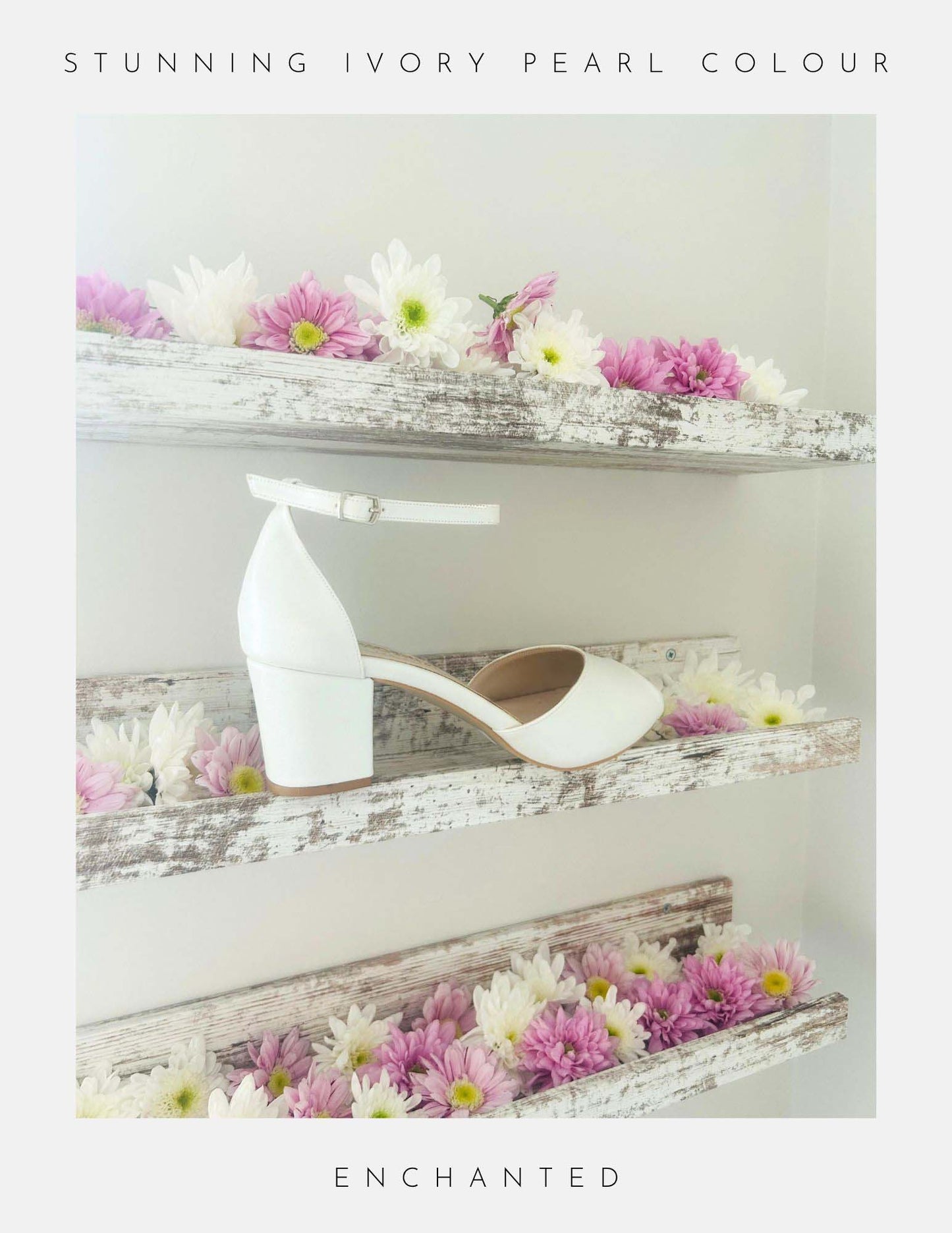 The Phoenix England Enchanted Peep Toe Low Bridal Shoes in pearl ivory vegan leather feature a peep toe, ankle strap, and low heel, displayed on a rustic shelf with pink and white daisies. Text: Stunning Ivory Pearl Colour, Enchanted.