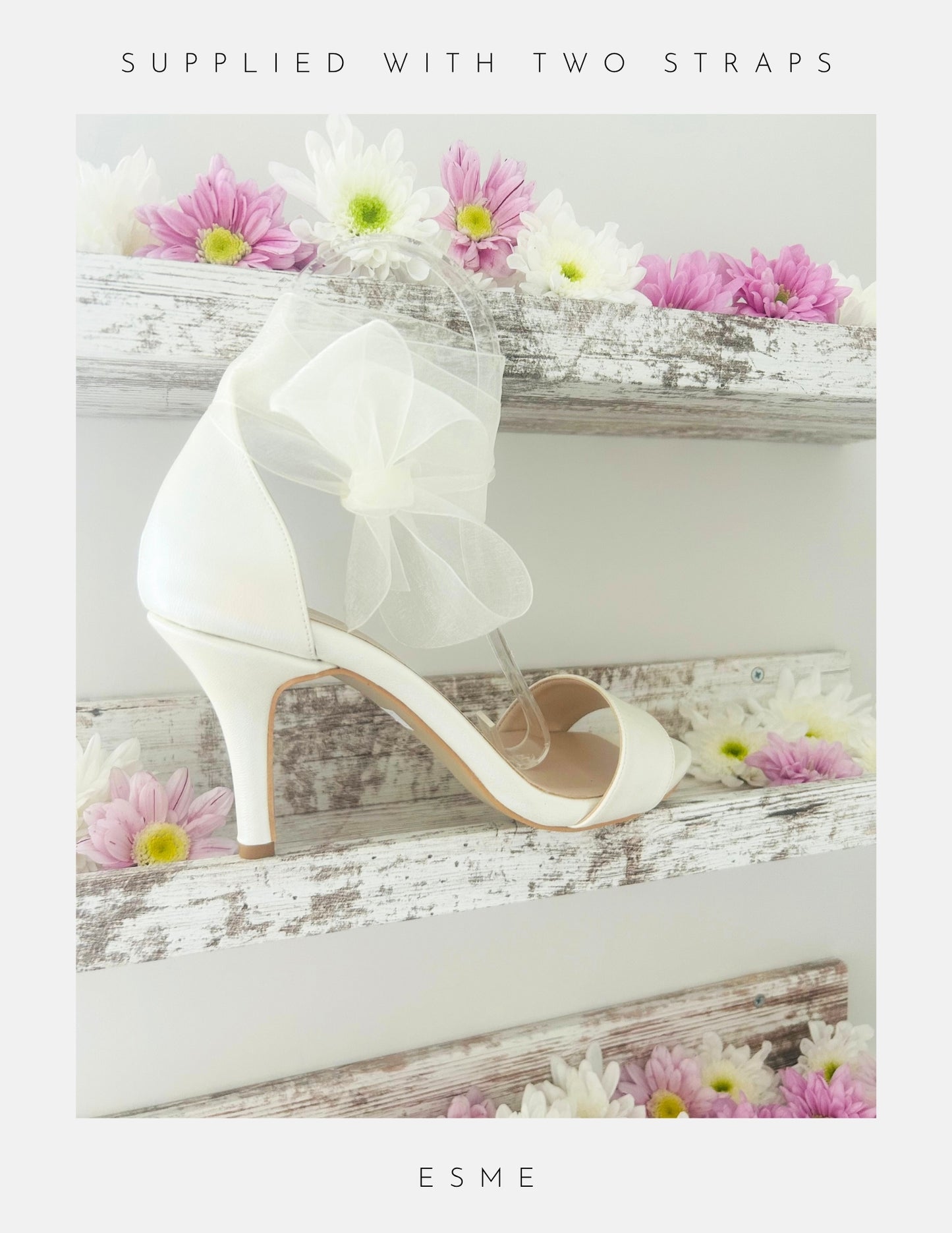 Ivory high-heeled shoe with a bow, placed on a wooden surface with flowers.