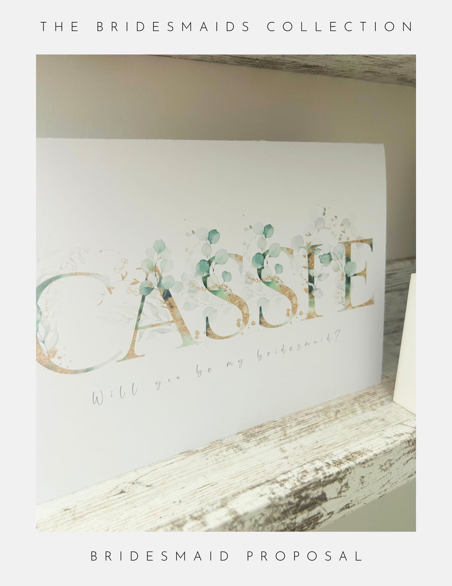 A card with Cassie in floral letters and Will you be my bridesmaid? sits on a rustic wooden shelf. From Phoenix England, the Maid Of Honour Proposal Sterling Silver is a charming choice for your special proposal.