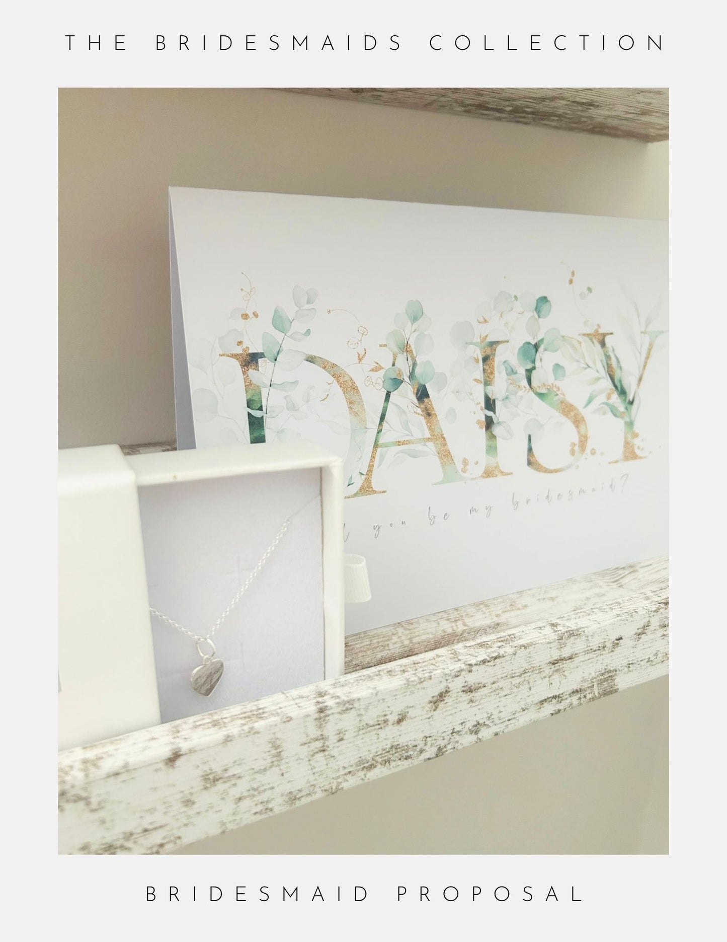 A card with the name Maid Of Honour in floral lettering sits on a wooden shelf beside a white box holding a heart-shaped sterling silver necklace by Phoenix England. Above: The Bridesmaids Collection; below: Bridesmaid Proposal.