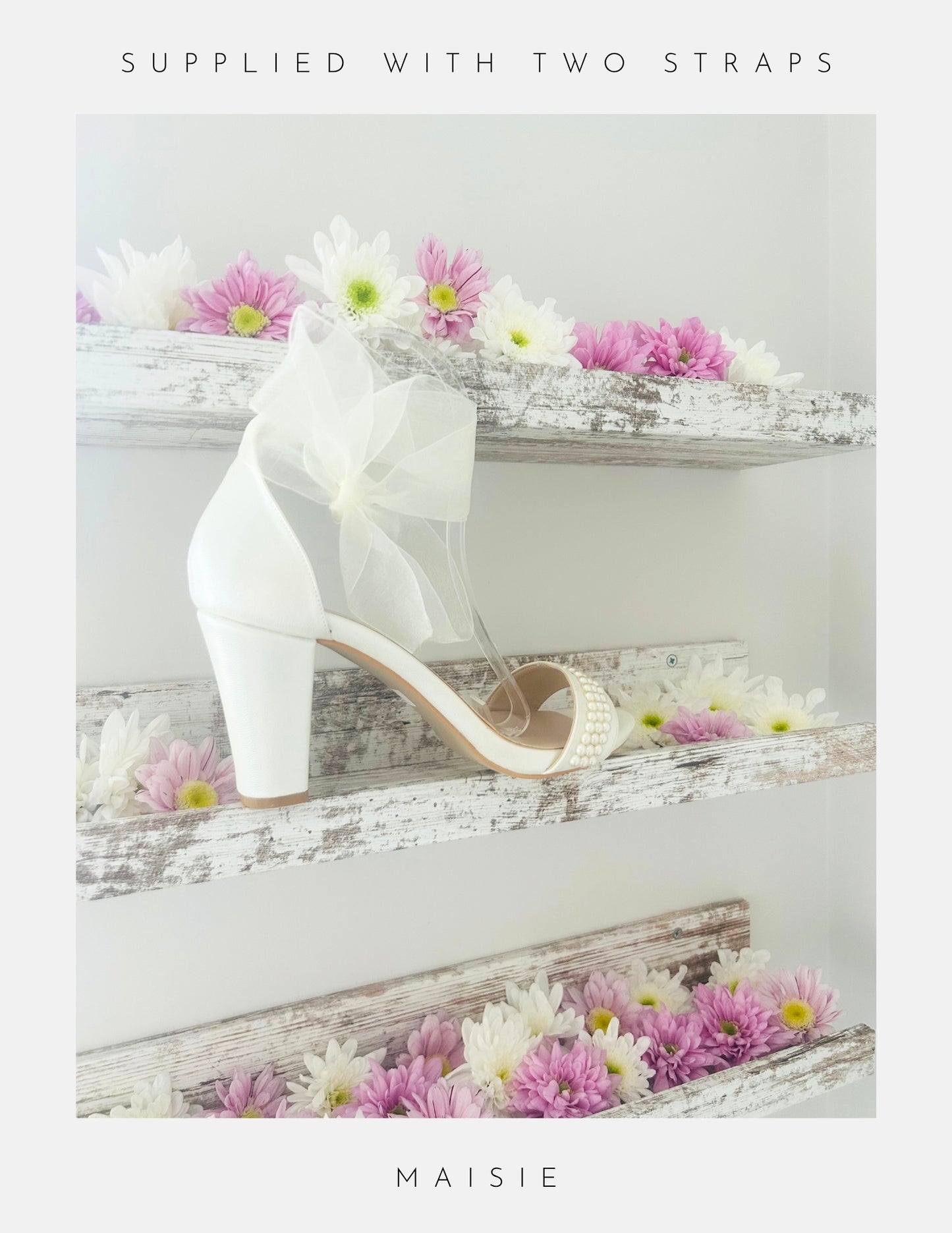 Ivory high-heeled shoe with a bow on a decorative wooden surface with flowers.