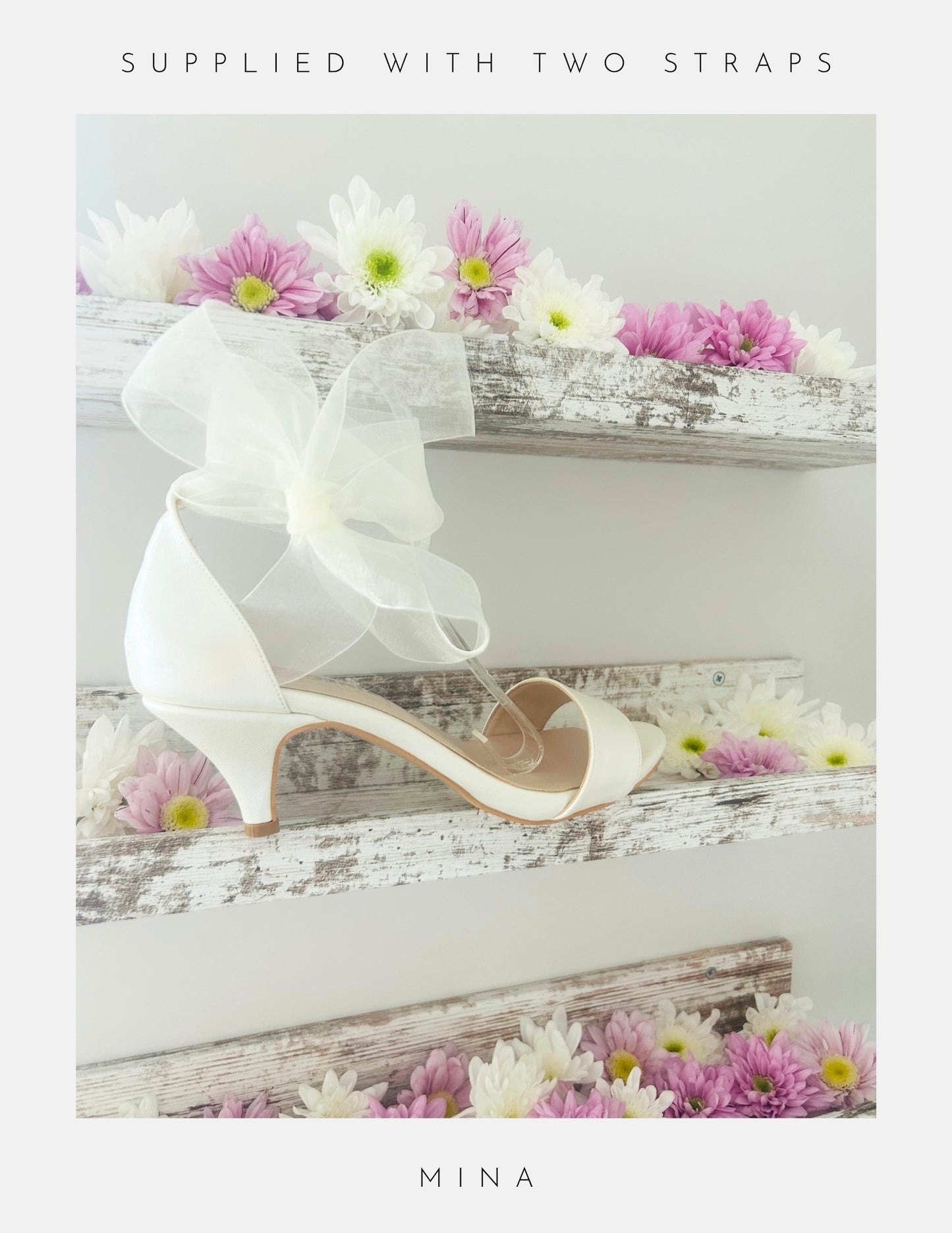 ivory high-heeled kitten heel bridal shoe with a bow and flowers on a wooden surface, branded 'Mina'.