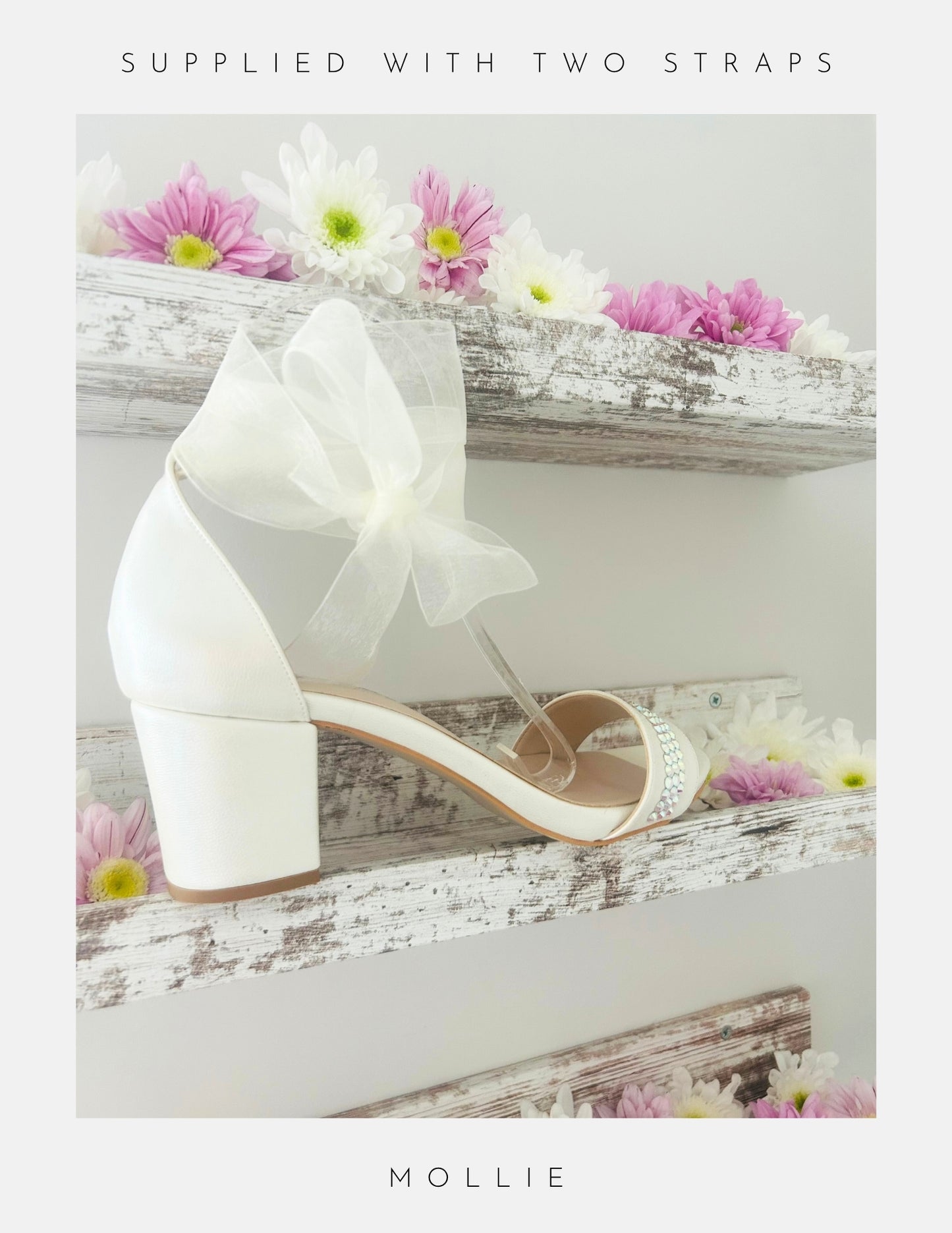 Ivory wedding shoe with an organza bow on a wooden surface with flowers