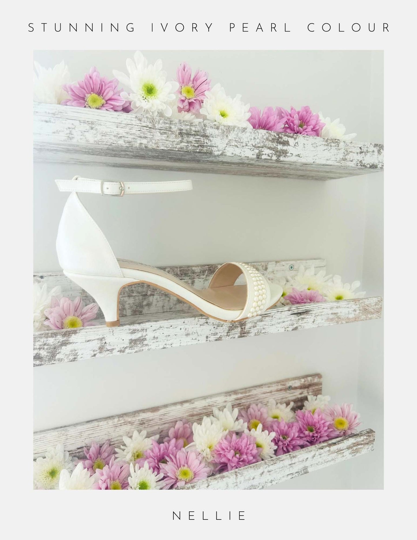 The Phoenix England Nellie Pearl Kitten Heel Bridal Shoes in ivory pearl are shown on a rustic wooden shelf with pink and white flowers. Text reads Stunning Ivory Pearl Colour above and Nellie below, perfect for brides.