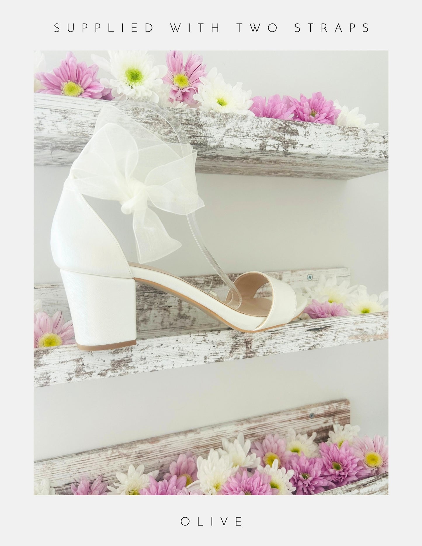 An Ivory block heel sandal, Phoenix England's Olive Block Heel Bridal Shoes with an organza strap, is shown on a rustic wooden shelf with pink and white flowers. Text: SUPPLIED WITH TWO STRAPS at top and OLIVE at bottom.
