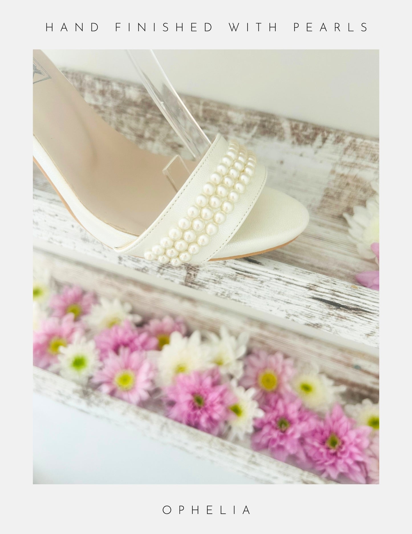 The Ophelia Pearl High Heel Wedding Shoes by Phoenix England, hand-finished with crystal pearls, rest on rustic wood amidst pink and white daisies. Perfect bridal heels for your big day.