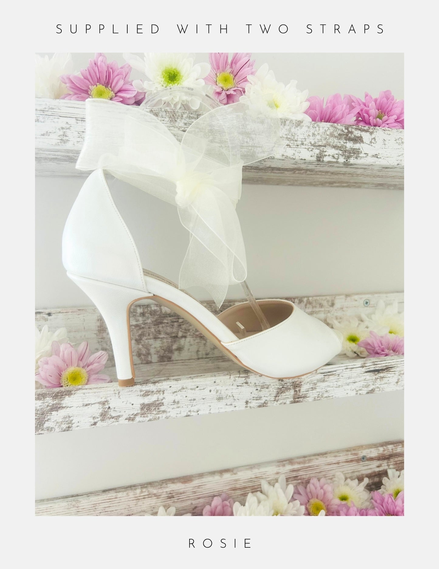 Ivory wedding shoe with floral decorations on a wooden surface with flowers.