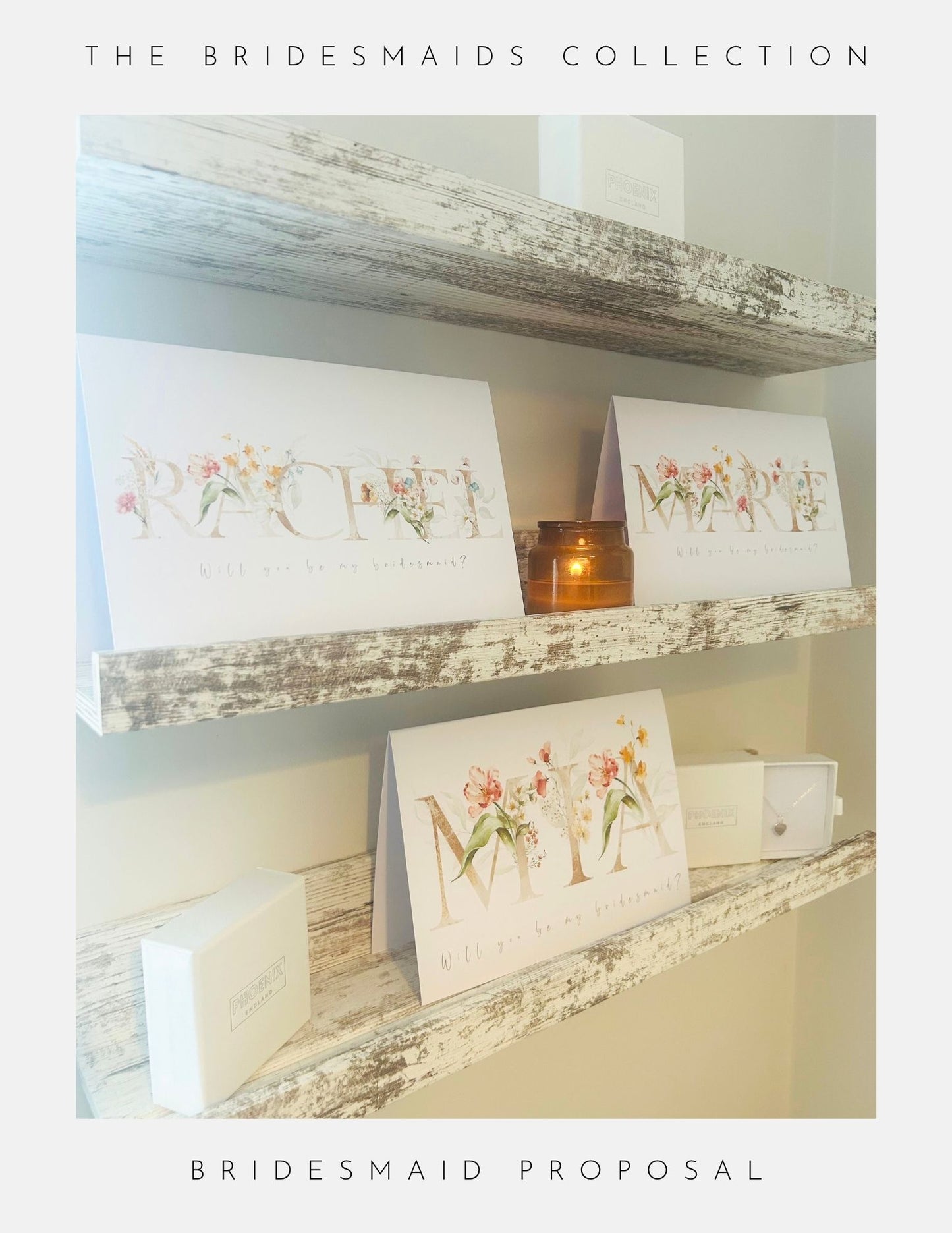 Three decorated “Will You Be My Bridesmaid” cards by Phoenix England sit on rustic shelves with white gift boxes and a lit candle, perfect for bridesmaid proposals. Text: “The Bridesmaids Collection - Bridesmaid Proposal.”.