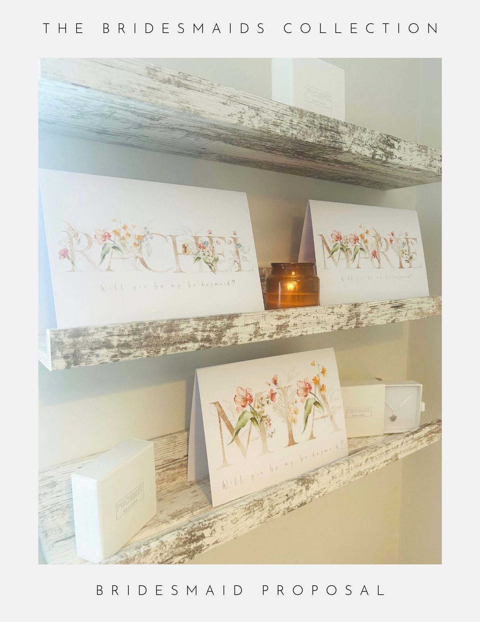 Three decorated “Will You Be My Bridesmaid” cards by Phoenix England sit on rustic shelves with white gift boxes and a lit candle, perfect for bridesmaid proposals. Text: “The Bridesmaids Collection - Bridesmaid Proposal.”.