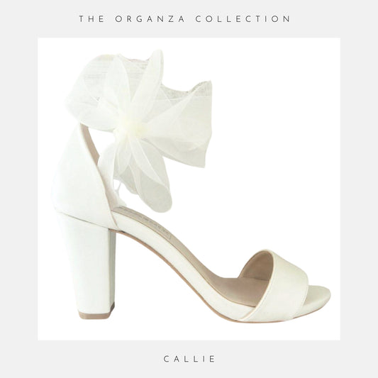 Ivory high-heeled shoe with ruffle detail from The Organza Collection on a light grey background.
