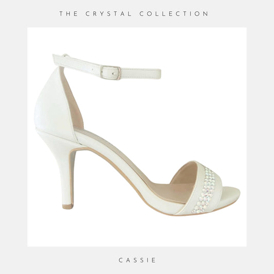 An ivory high heel bridal shoe with ankle strap, open toe and 3 rows of crystals to the front.