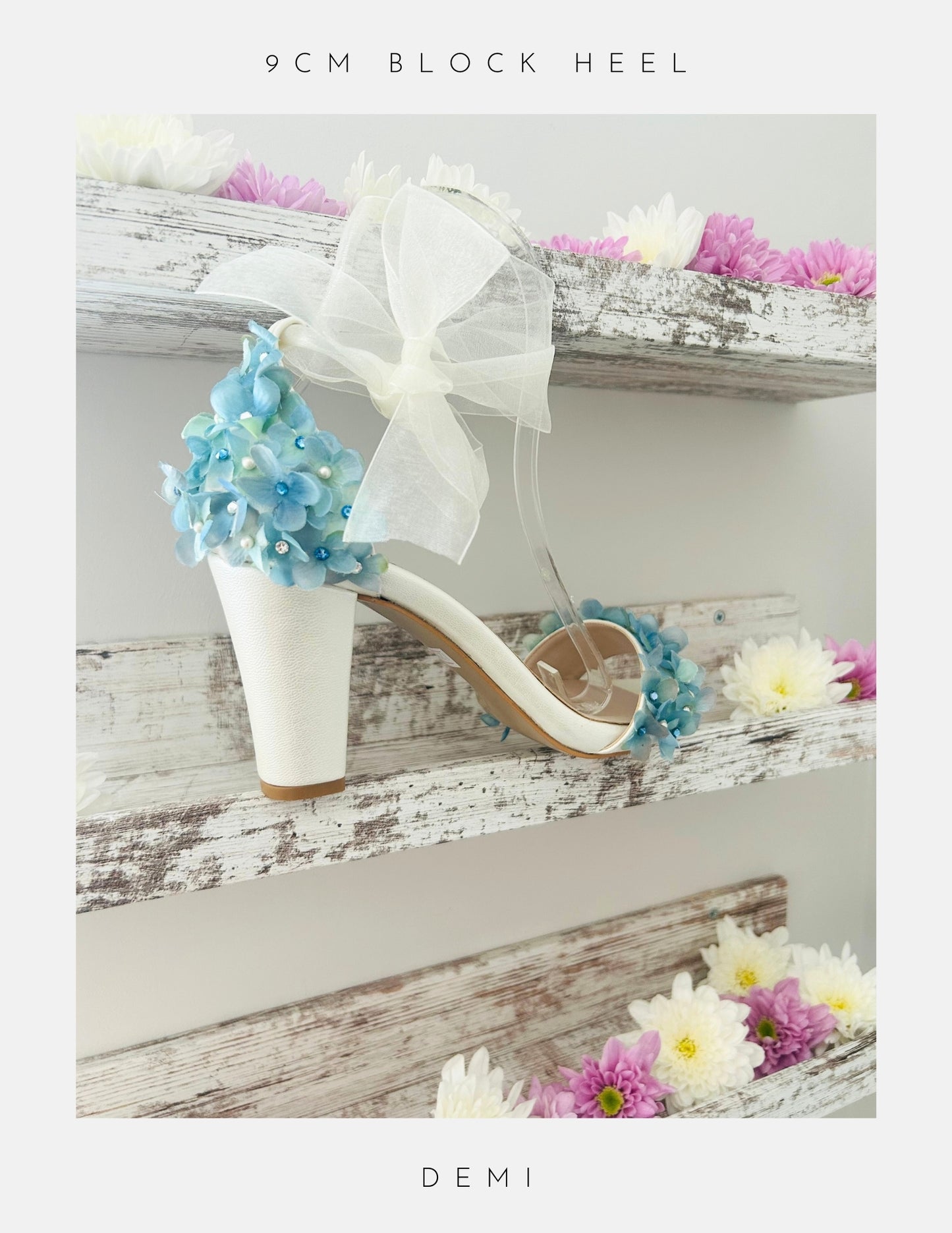 Ivory high-heeled shoes with floral decorations on a wooden shelf with flowers.