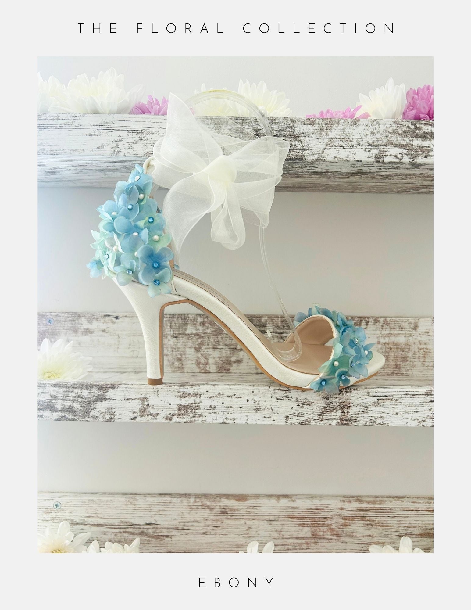 Ivory high-heeled bridal shoes with floral decorations on a wooden surface, labelled 'The Floral Collection' and 'Ebony'.