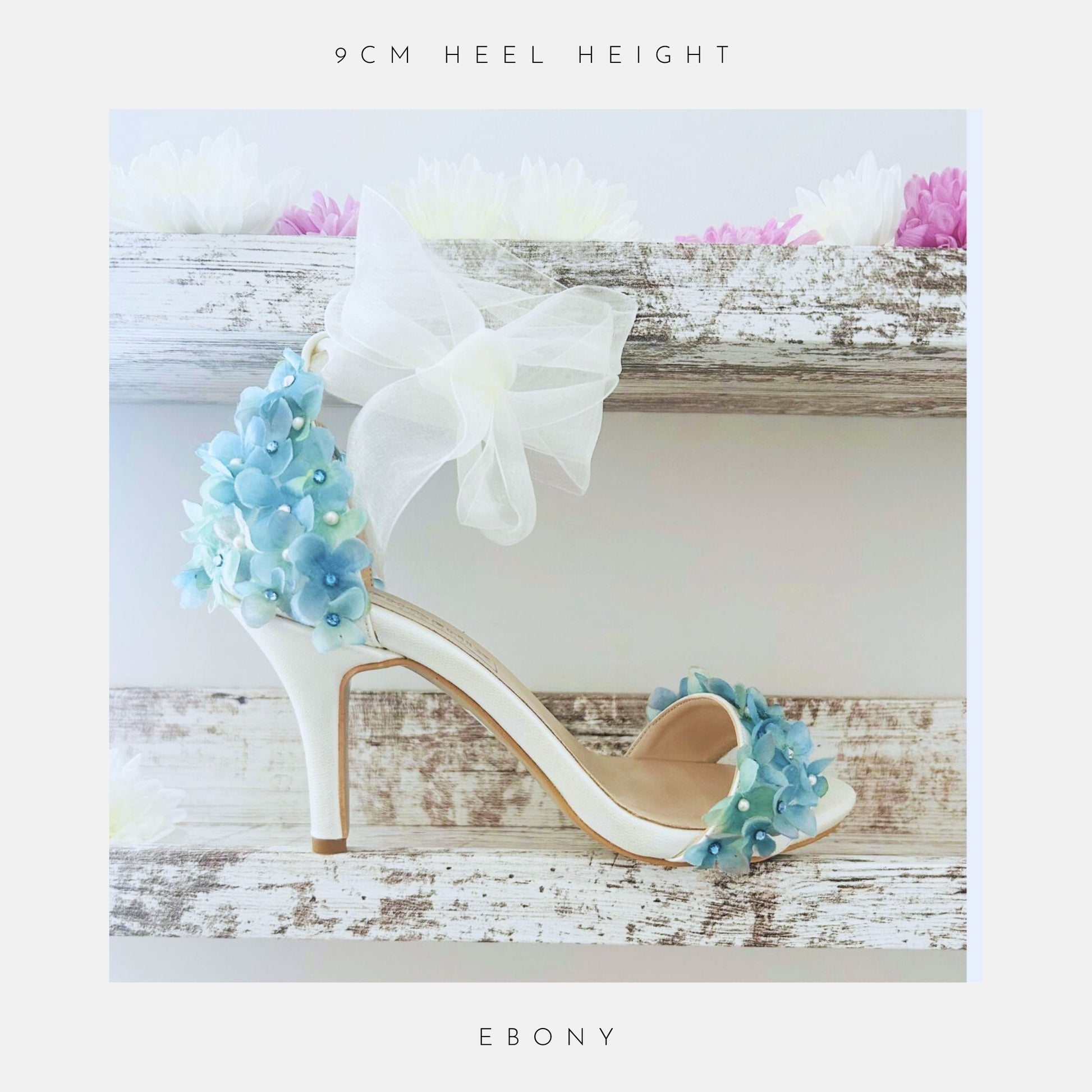 Ivory high-heeled bridal shoes with floral decorations on a wooden surface, labelled '9cm heel height' and 'Ebony'.