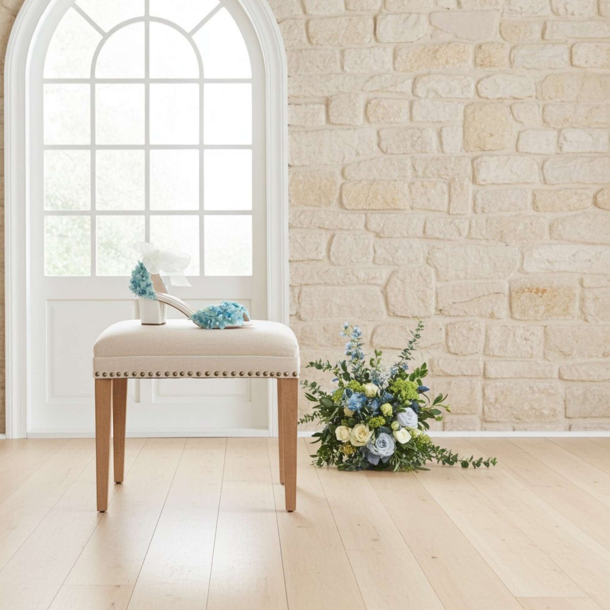 Stool with blue floral peep toe low block bridal shoes with bouquet of blue and cream flowers.