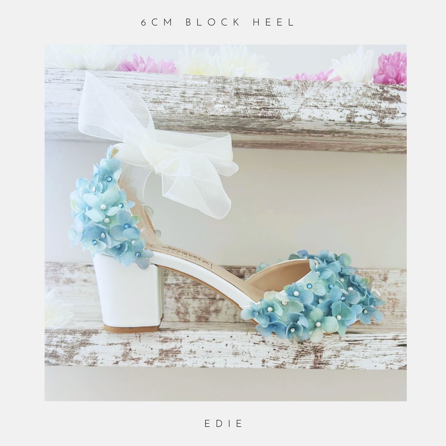 Ivory bridal sandal with blue floral decorations on a wooden surface, labelled '6cm block heel' and 'Edie'.