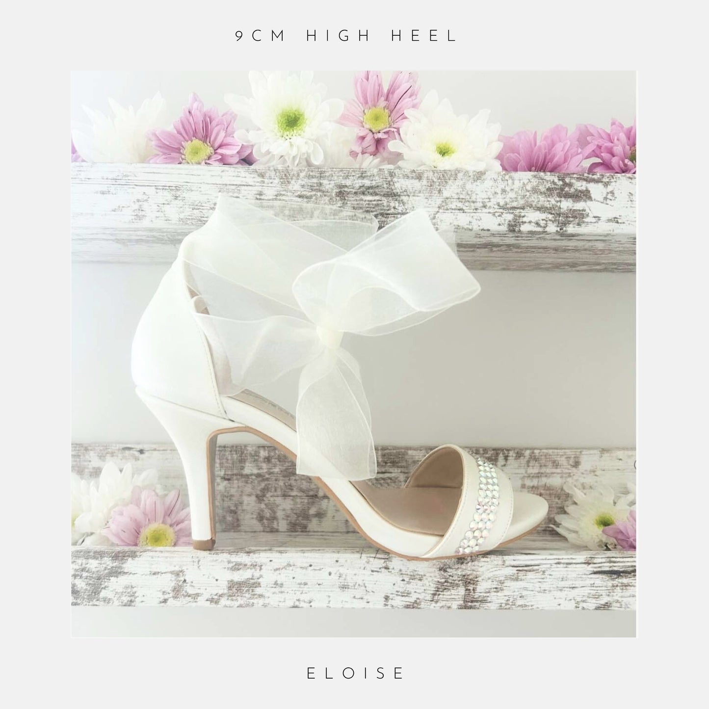 Ivory high-heeled wedding shoes with a bow on a wooden surface with flowers, labelled '9cm high heel' and 'Eloise'.
