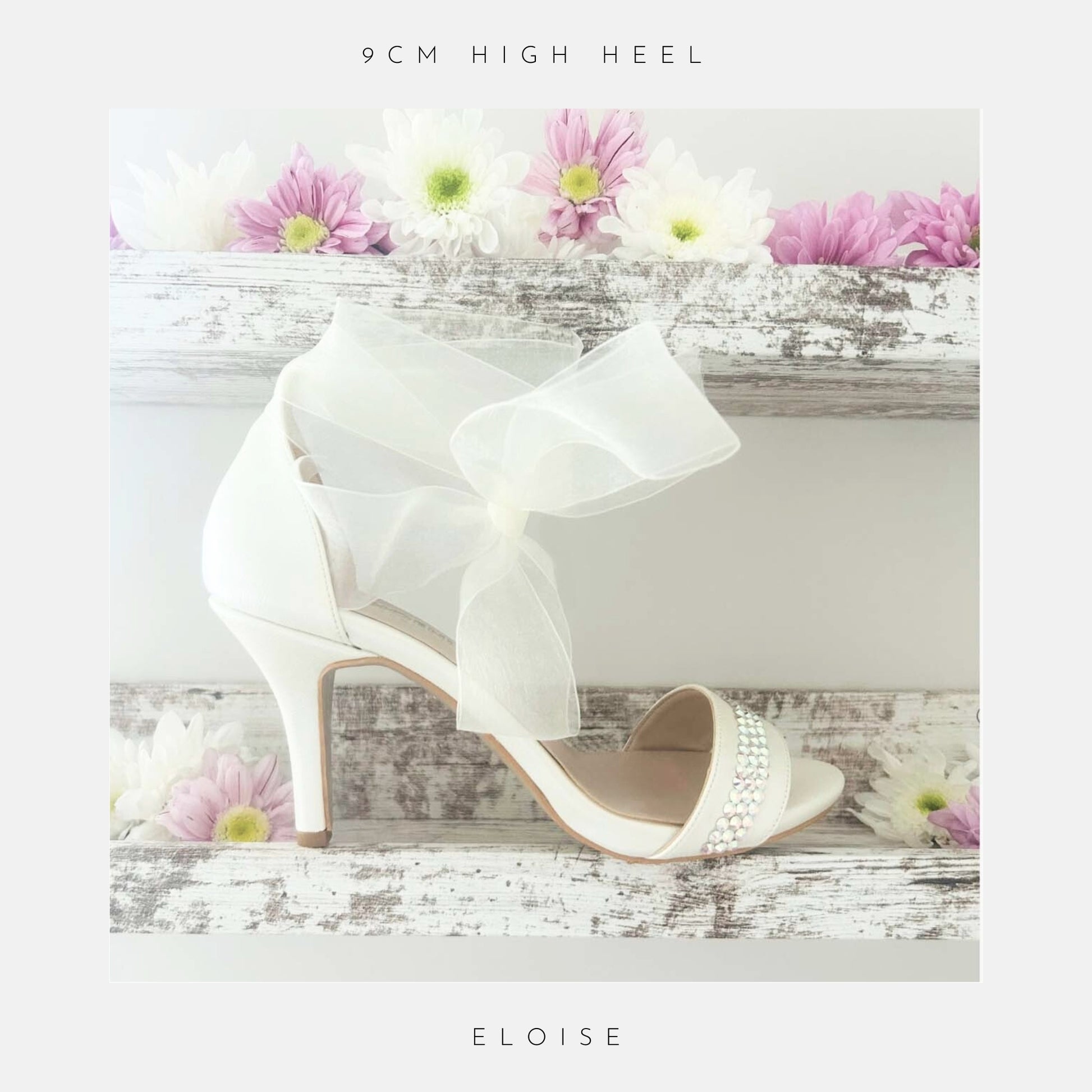 Ivory high-heeled wedding shoes with a bow on a wooden surface with flowers, labelled '9cm high heel' and 'Eloise'.