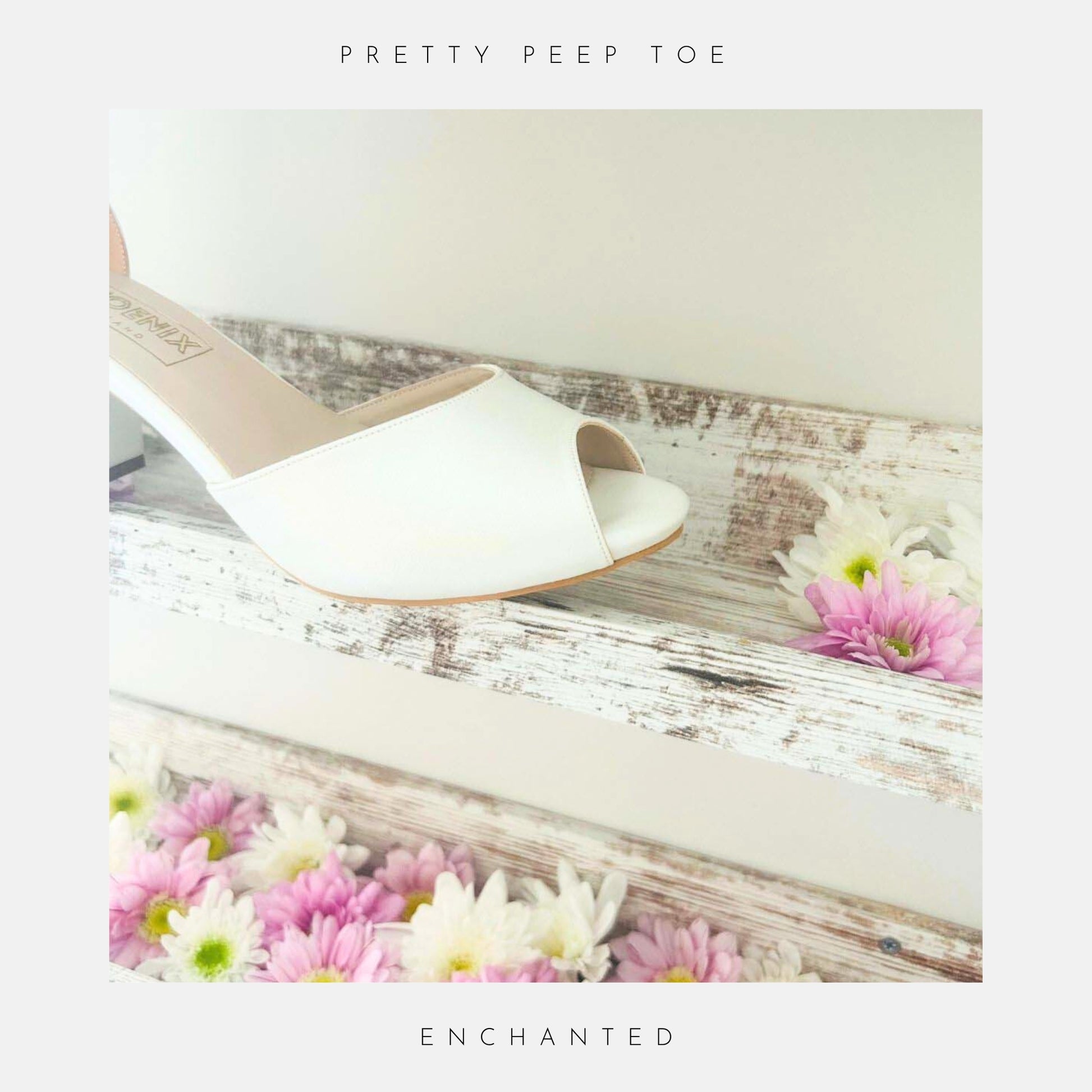 The Enchanted Peep Toe Low Bridal Shoes from Phoenix England, crafted in pearl ivory vegan leather, sit on top of a rustic wooden shelf with pink and white flowers.