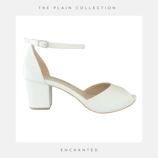 Ivory high-heeled shoe with 'The Plain Collection' branding on a light grey background.