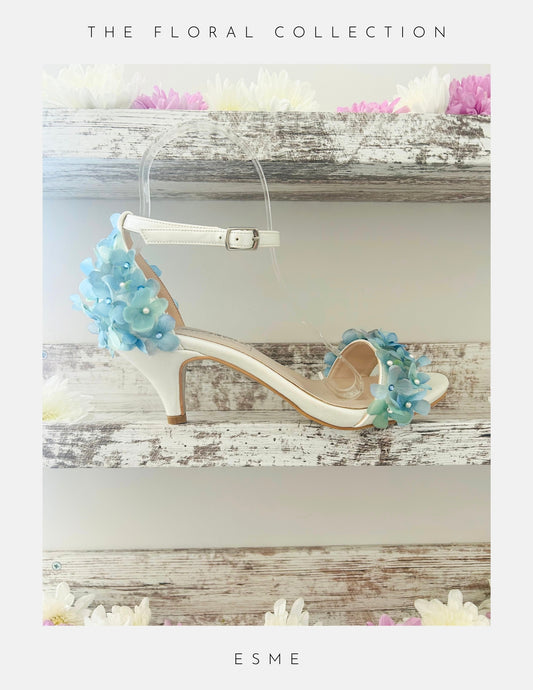 ivory kitten heel bridal shoe with floral decorations on a wooden surface, labelled 'ESME'.