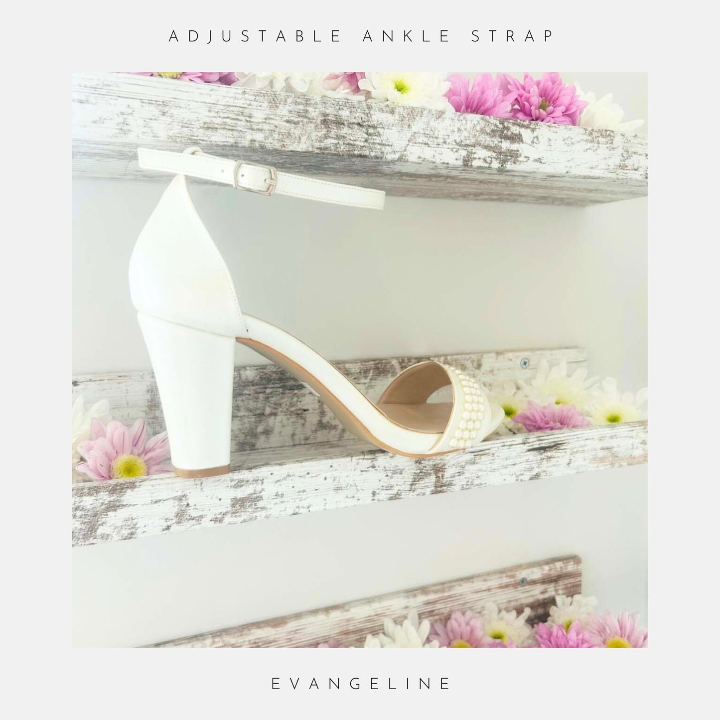 A single Evangeline Pearl Block Heel Wedding Shoe by Phoenix England, in ivory pearl, with ankle strap, sits on a rustic white shelf decorated with pink and white daisies. Text: Adjustable ankle strap and Evangeline.
