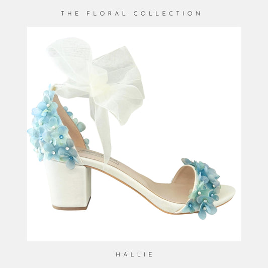 Ivory bridal sandal with floral decorations on a light grey background