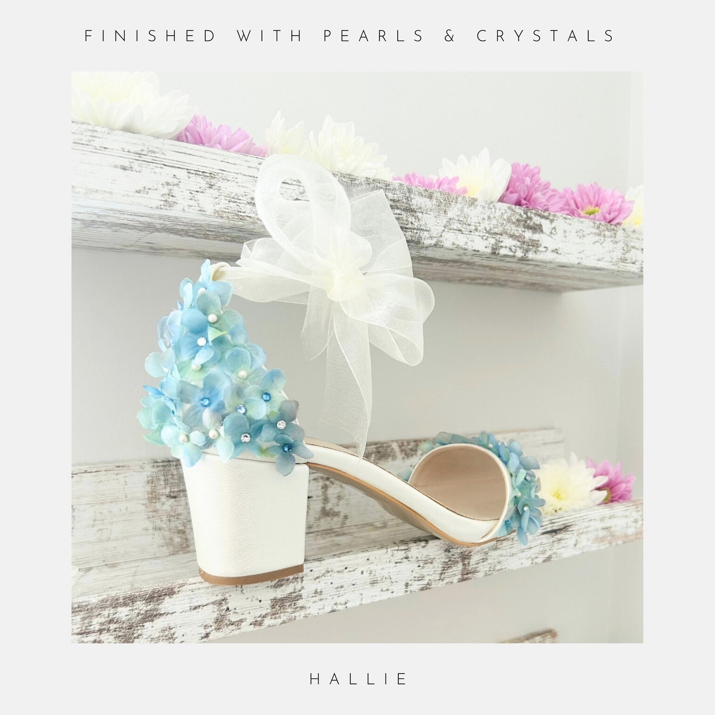 Ivory wedding sandal with floral decorations on a wooden shelf with flowers.