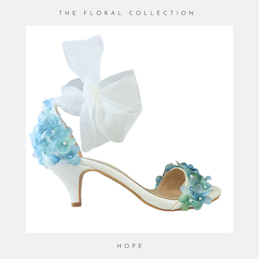Kitten heel ivory bridal shoes finished with blue hydrangeas and pearls and an organza ankle strap.