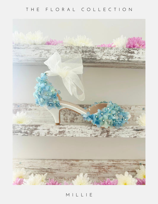 Floral embellished high-heeled bridal shoes on a wooden surface with 'The Floral Collection' text.