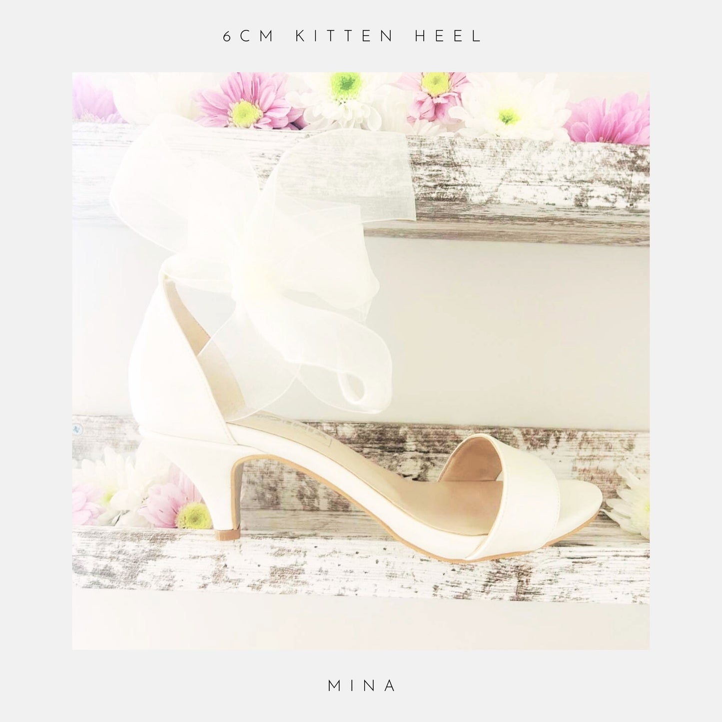 Ivory open toe kitten heel bridal sandal with an organza bow on a wooden surface with flowers, labelled '6cm kitten heel' and 'Mina'.