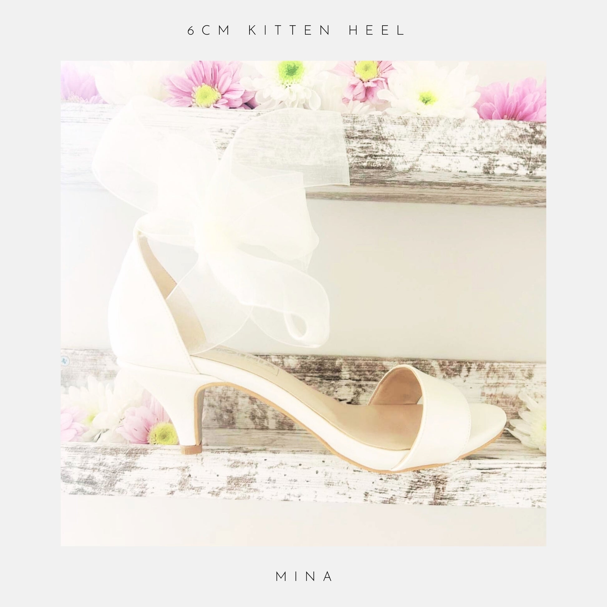 Ivory open toe kitten heel bridal sandal with an organza bow on a wooden surface with flowers, labelled '6cm kitten heel' and 'Mina'.