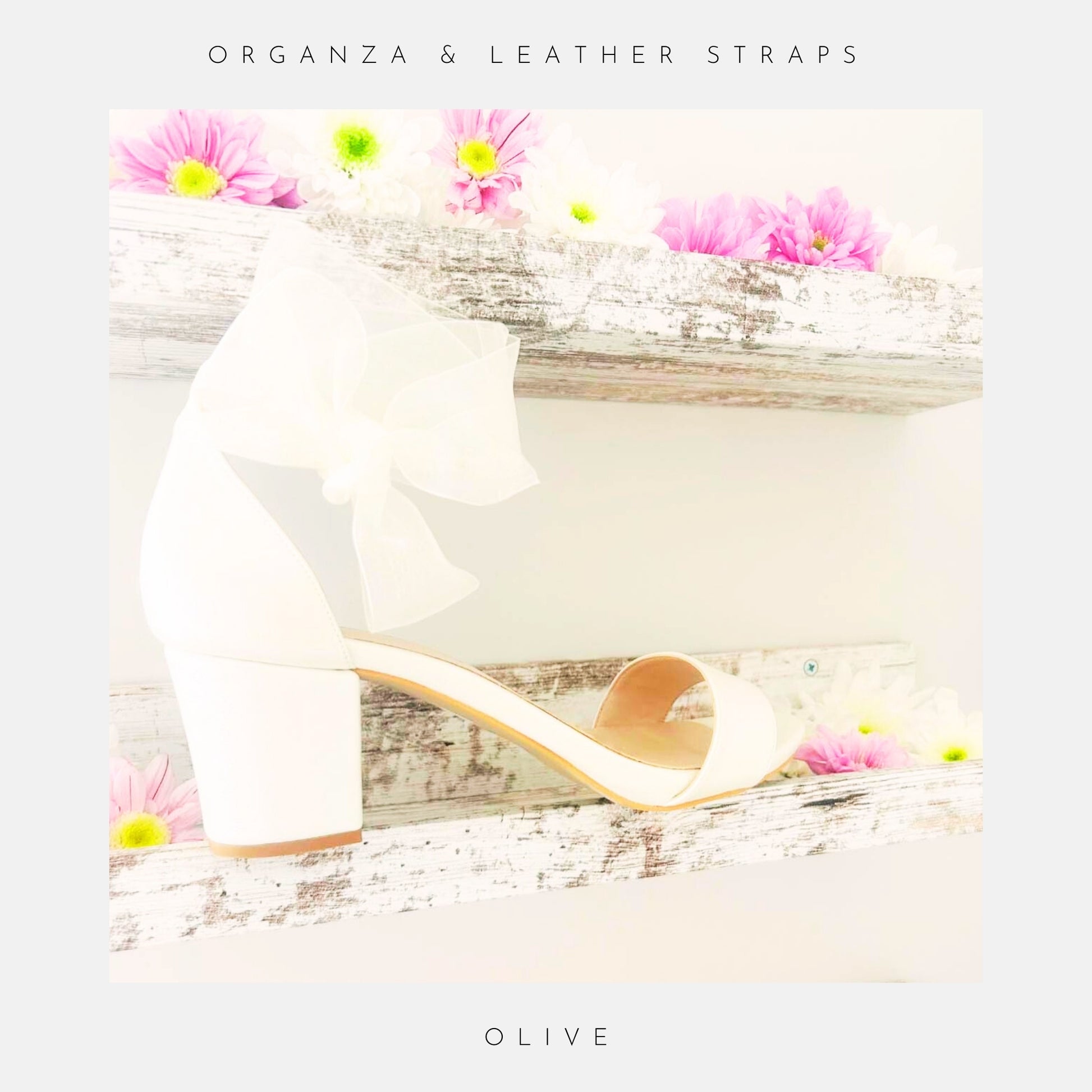 An Ivory block heel sandal, Phoenix England's Olive Block Heel Bridal Shoes with an organza strap, is shown on a rustic wooden shelf with pink and white flowers. Text: ORGANZA & LEATHER STRAPS at top and OLIVE at bottom.
